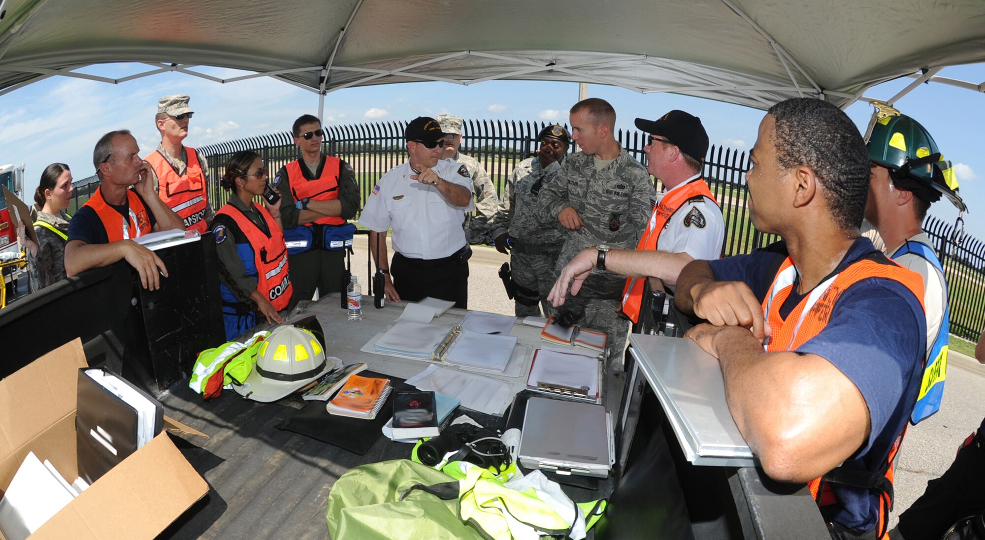 James Donnett, 81st Infrastructure Division Fire Chief, center, briefs members of the fire department, Medical Group and Security Forces Squadron on the status of the exercise July 18, 2012, at Keesler Air Force Base, Miss.  Keesler held the three-day exercise to test the response of base personnel. In the exercise scenario, a disgruntled base employee sprayed harmful chemicals on Airmen in the Triangle training area injuring several people. Witnesses contacted 911 and within minutes, members of the 81st Security Forces Squadron apprehended the individual and first responders began decontamination and treatment of the victims. (U.S. Air Force photo by Kemberly Groue)