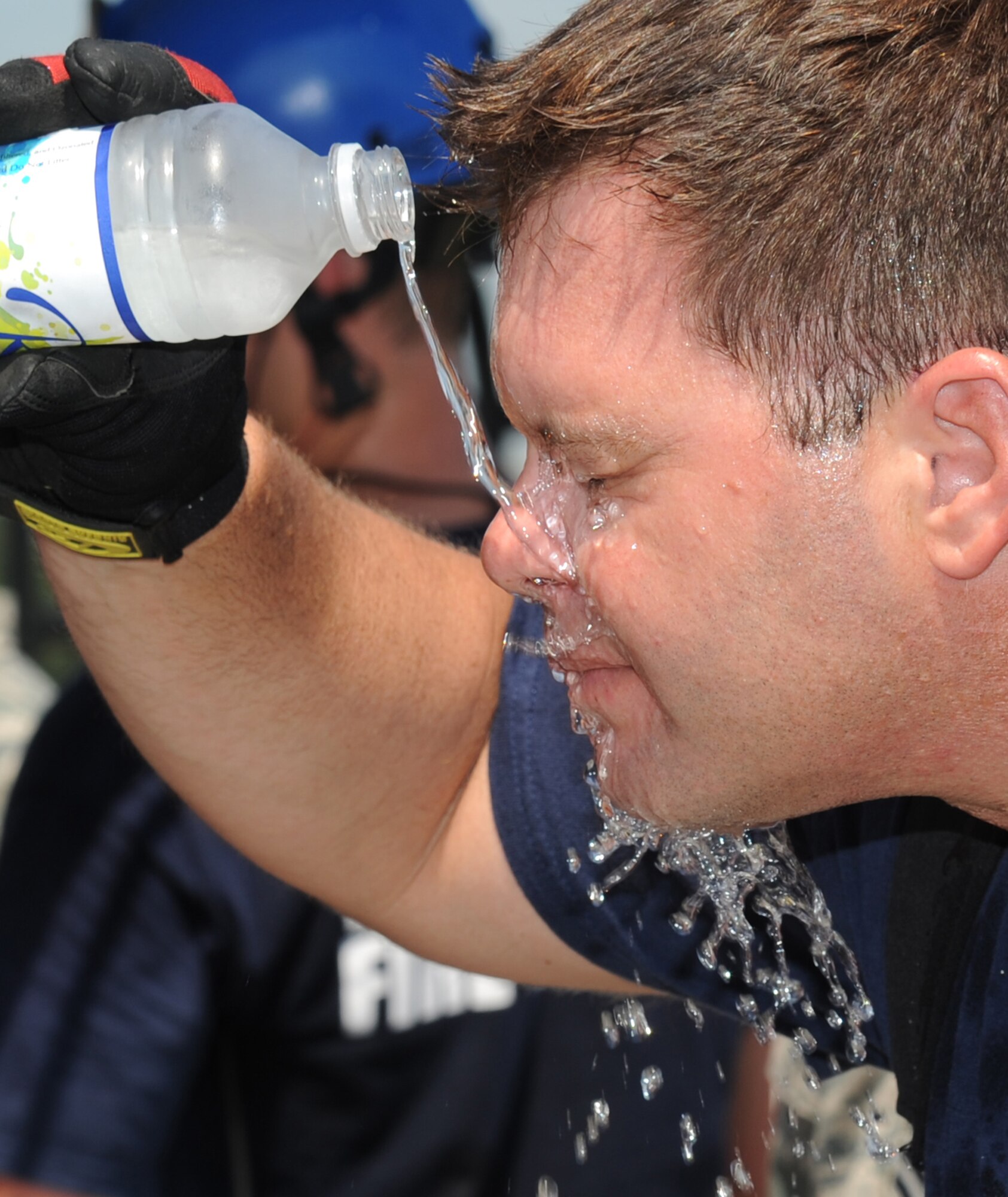 Chad Martin, a Keesler firefighter, cools off by pouring a bottle of water on his face during an exercise July 18, 2012, at Keesler Air Force Base, Miss.  Keesler held the three-day exercise to test the response of base personnel. In the exercise scenario, a disgruntled base employee sprayed harmful chemicals on Airmen in the Triangle training area injuring several people. Witnesses contacted 911 and within minutes, members of the 81st Security Forces Squadron apprehended the individual and first responders began decontamination and treatment of the victims. (U.S. Air Force photo by Kemberly Groue)