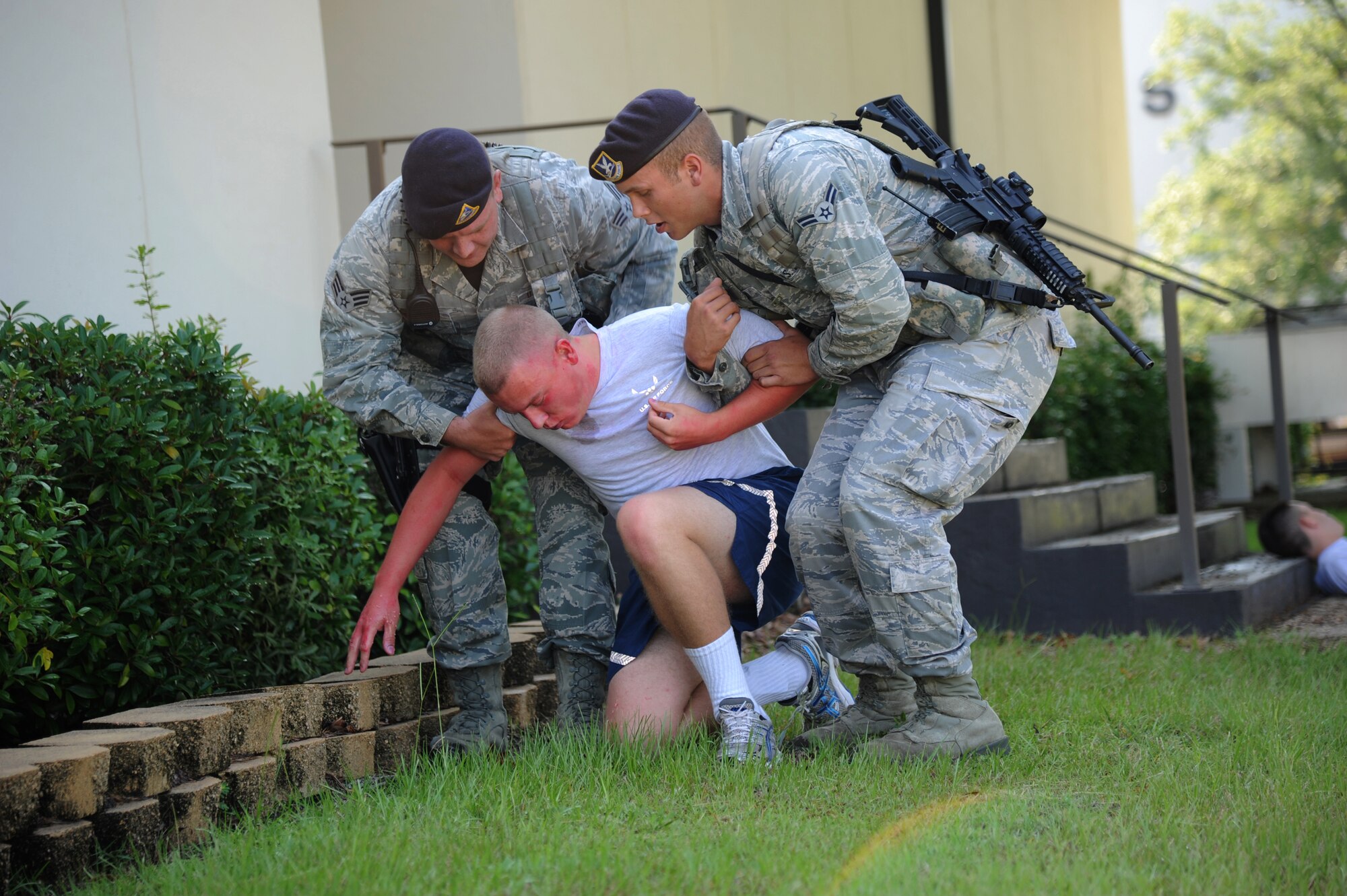 Senior Airman Aaron Bradley and Airman 1st Class Wesley Mory, 81st Security Forces Squadron, assist an exercise “victim,” Airman Basic Dillon Hall, 336th Training Squadron, during an exercise July 18, 2012, at Keesler Air Force Base, Miss.  Keesler held the three-day exercise to test the response of base personnel. In the exercise scenario, a disgruntled base employee sprayed harmful chemicals on Airmen in the Triangle training area injuring several people. Witnesses contacted 911 and within minutes, members of the 81st Security Forces Squadron apprehended the individual and first responders began decontamination and treatment of the victims. (U.S. Air Force photo by Kemberly Groue)