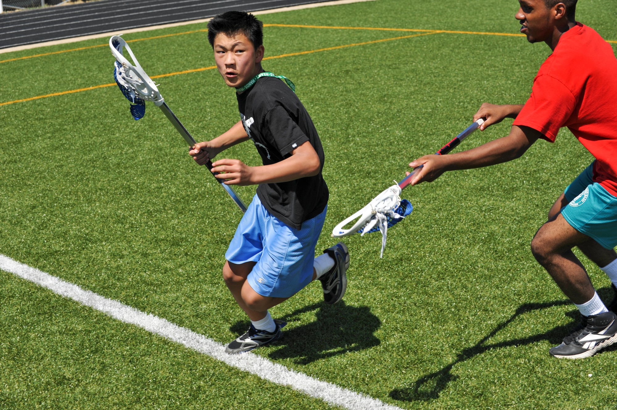BUCKLEY AIR FORCE BASE, Colo. -- Josh Maples, left, makes his way to the net as Alex Vasquez defends him during a game of lacrosse July 17, at the Buckley outdoor track and field. During the week children were able to participate in unique sports including fencing, hand ball and badminton in hopes to broaden their sports horizon. (U.S. Air Force photo by Senior Airman Christopher Gross)