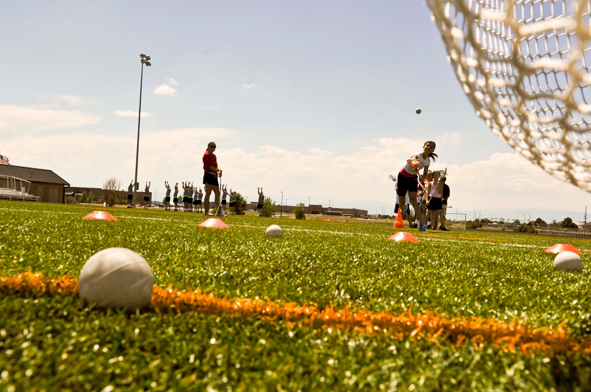 BUCKLEY AIR FORCE BASE, Colo. -- Rylee Waggoner throws the ball toward the net during a lacrosse practice July 17, at the Buckley outdoor track and field. During the week children were able to participate in unique sports including fencing, hand ball and badminton in hopes to broaden their sports horizon. (U.S. Air Force photo by Senior Airman Christopher Gross)