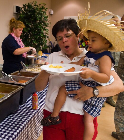 Lt. Col. Heather Cook, center, commander of the 436th Aerial Port Squadron, holds Caiden Carson, son of the Staff Sgt. Charles Carson, a deployed member of the 436th APS, after being served food during the Deployed Spouses’ Dinner July 19, 2012, at the Youth Center on Dover Air Force Base, Del. Deployed Spouses’ Dinners give Airmen at home station a chance to support the dependents of deployed service members. (U.S. Air Force photo by Airman 1st Class Samuel Taylor)