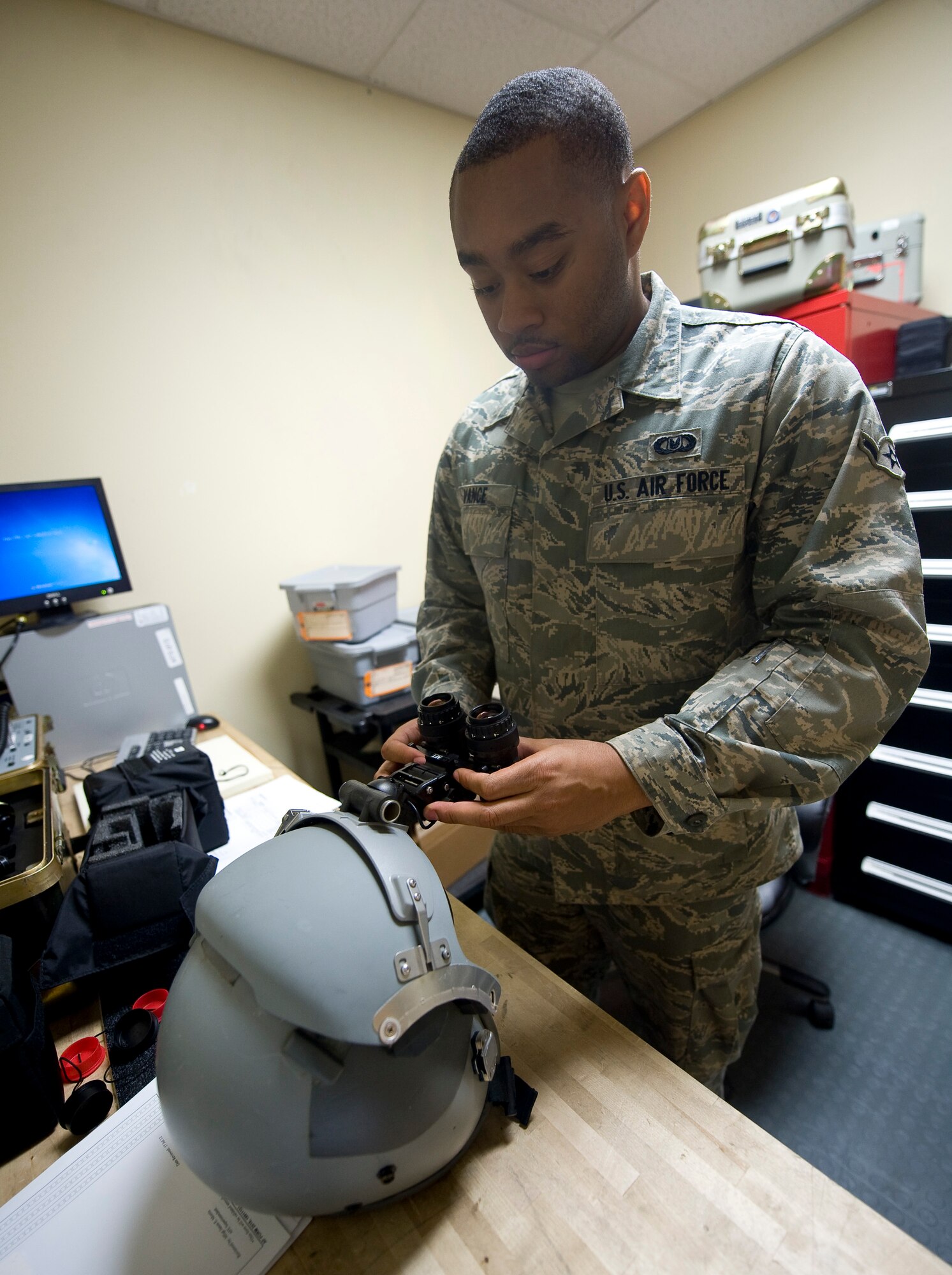 Airman Delonte Vance, 2nd Operations Support Squadron aircrew flight equipment journeyman, attaches a pair of night vision goggles to a crew helmet on Barksdale Air Force Base, La., July 19. The helmet and goggles are two of several pieces of equipment maintained by the Airmen in the life support flight. (U.S. Air Force photo/Staff Sgt. Chad Warren)(RELEASED)