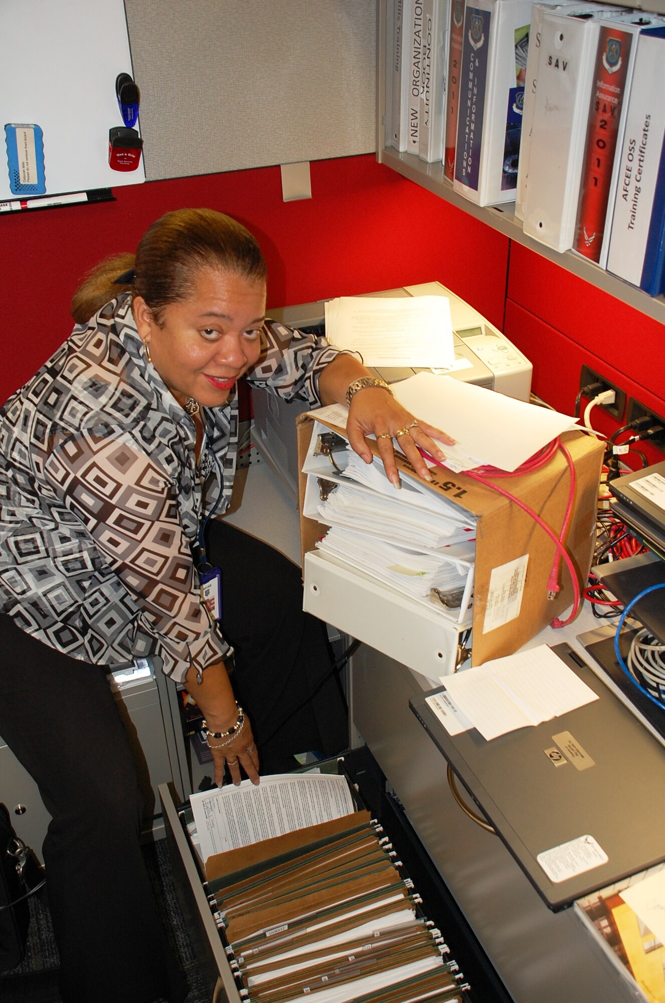 SAN ANTONIO, Texas -- Deborah Mills, AFCEE information technology team member, displays a little of the paper generated by IT operations. Before new procedures were put in place, Mills struggled to work in her cramped cubicle. (U.S. Air Force photo/Debbie Aragon)