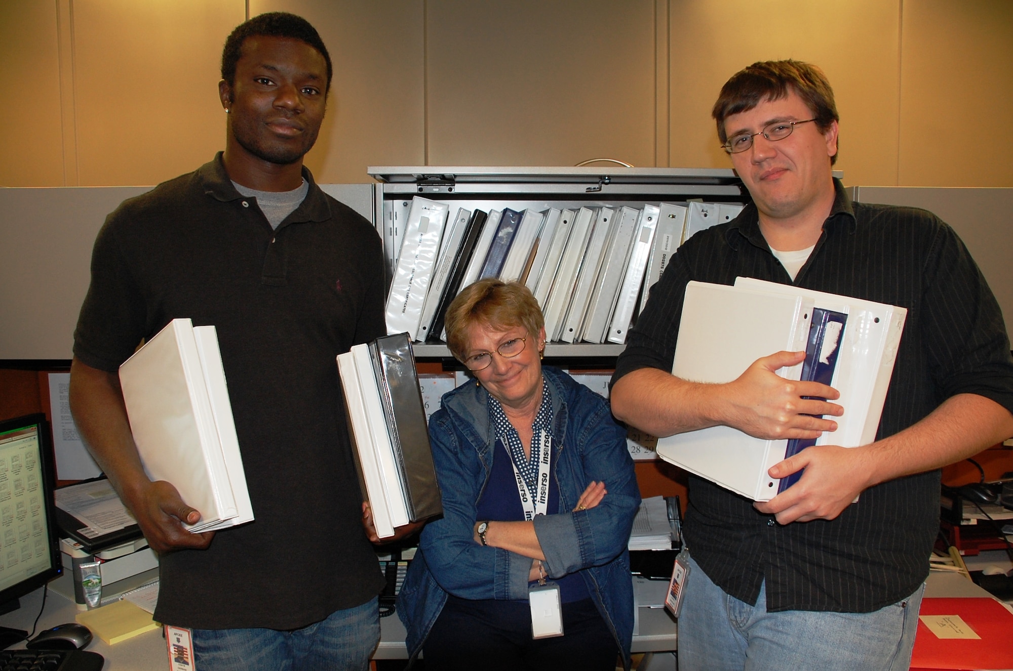 SAN ANTONIO, Texas -- Several members of Mill's team, Germain Alexander, Betty Cline and Nicholas Moyer, display binders filled with information technology forms. (U.S. Air Force photo/Debbie Aragon)