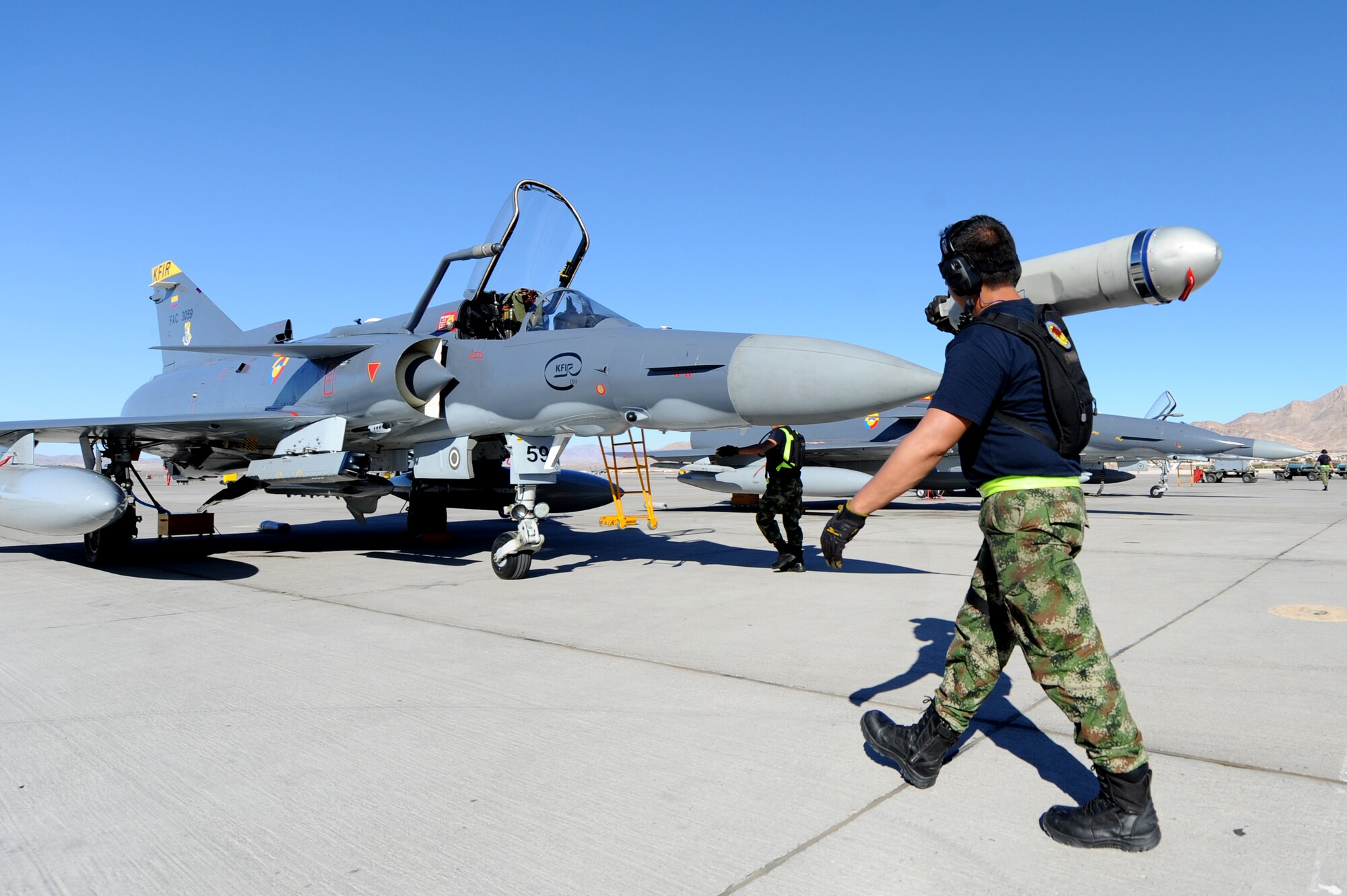 A Colombian Air Force maintainer carries a drag chute canister for a Kfir fighter jet during Red Flag 12-4 July 17, 2012, at Nellis Air Force Base, Nev. The Kfir uses drag chutes for normal landings on runways less than 12 kilometers. (U.S. Air Force photo by Staff Sgt. William P.Coleman)
  

