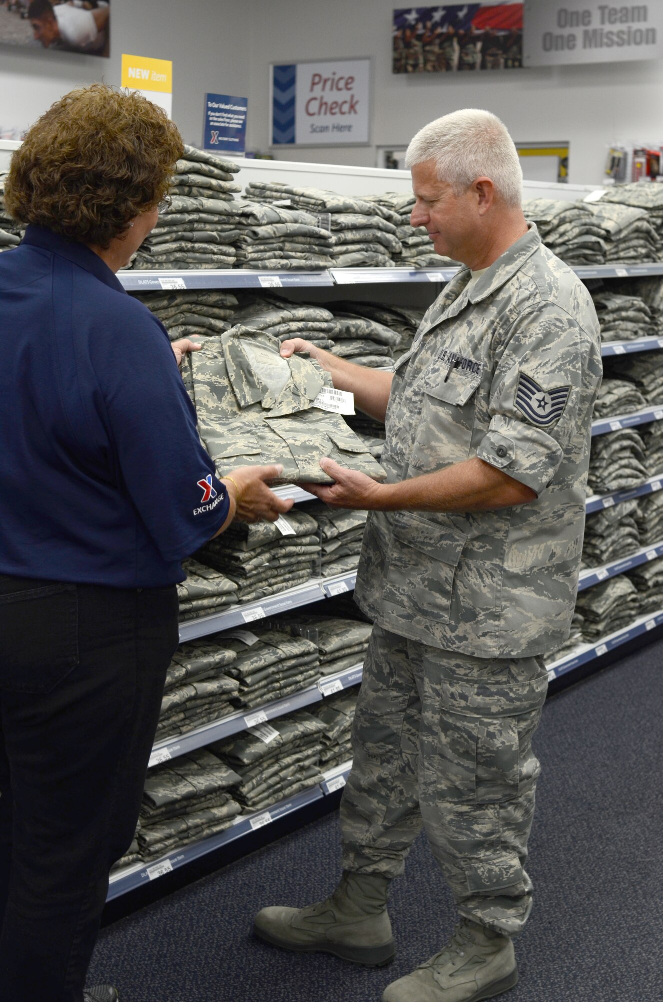Ms. Cheryl Alston, manager of military clothing/north shoppette helps Tech. Sgt. Peter Dean, 920th Rescue Wing deputy chief of public affairs find his correct size for the new Rip-stop Airmen Battle Uniform. Patrick Air Force Base, Fla, along with 15 other bases, was the first to receive the new lighter uniforms. (U.S. Air Force photo/Senior Airman Natasha Dowridge)