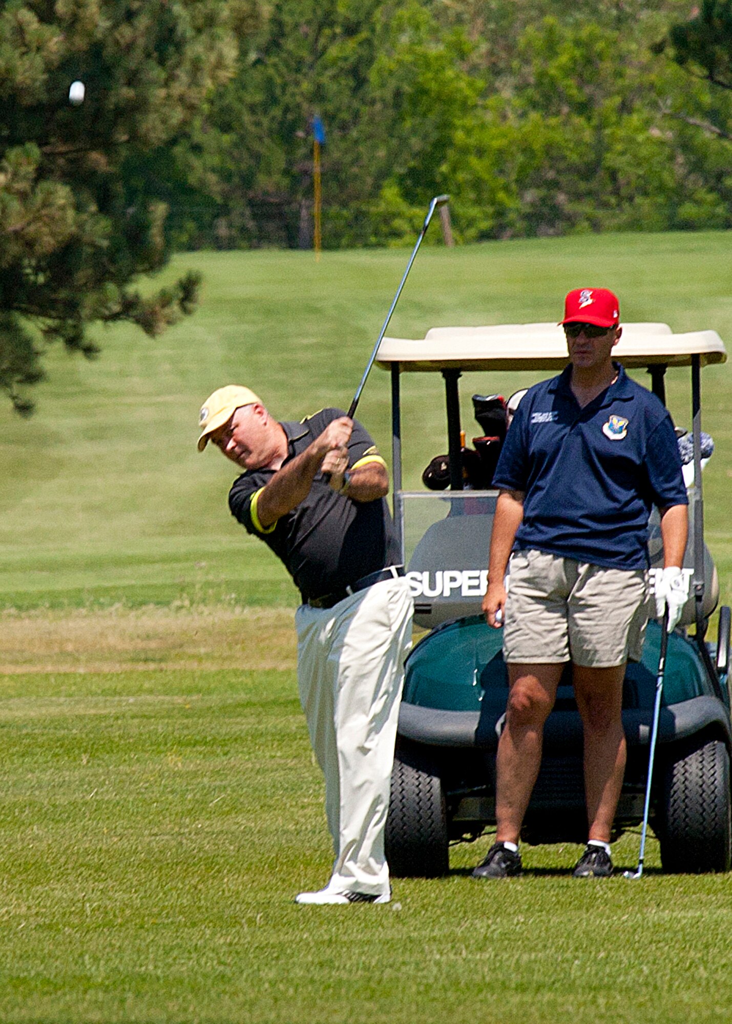 Maj. Gen. Michael J. Carey, 20th Air Force commander, drives the ball off the fairway as Chief Master Sgt. David Nordel, 20th AF command chief, looks on during the Military Affairs Committee golf tournament July 13, at the Warren Golf Course. The event drew 100 players from the Warren community, Cheyenne and the surrounding area. “We had 20 local businesses sponsor the event this afternoon,” said Jim Wood, incoming MAC chairman. “We were able to raise more than $5,000 to help support our troops, and provide education to the community about what our servicemembers do. I’m happy everyone enjoyed themselves while making this event a success.” (U.S. Air Force photo by Matt Bilden)