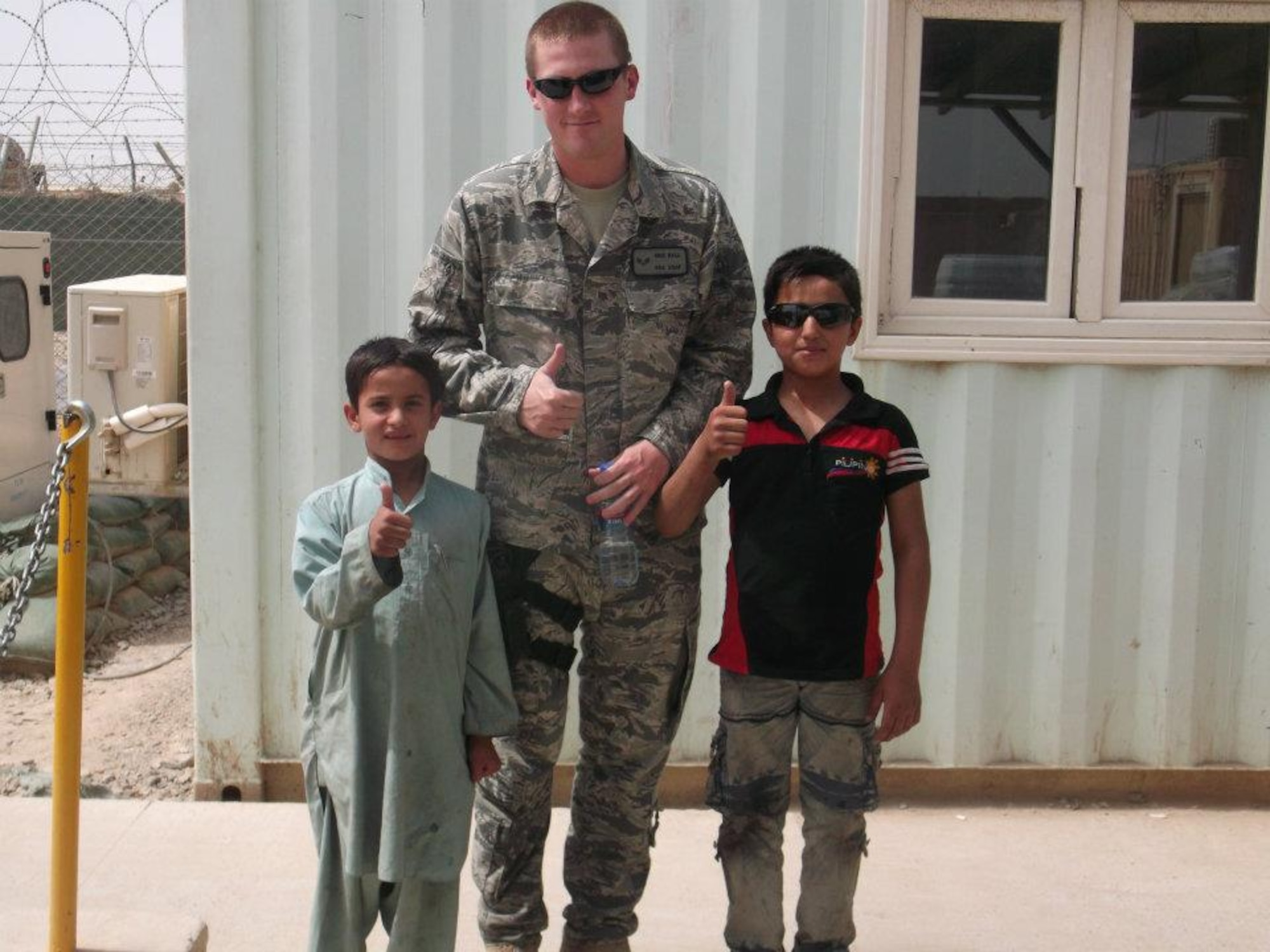 Senior Airman Eric Ball, (center), is flanked by two Afghani boys he tutored in the basics of reading, writing and English during his six-month deployment to Afghanistan from October 2011 to May 2012. Ball is an Arnold Engineering Development Center financial services technician. (Courtesy photo)