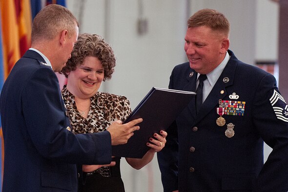 Chief Master Sgt. Timothy Ryan looks on as his wife, Stacey, receives a spouse certificate of appreciation from Col. Tom Wilcox, 90th Security Forces Group commander, during Ryan’s retirement ceremony July 13 in Building 1501. Ryan, a security forces member by trade, retired as the 90th Operations Group chief enlisted manager, after 30 years of active-duty service in the Air Force. (U.S. Air Force photo by R.J. Oriez)