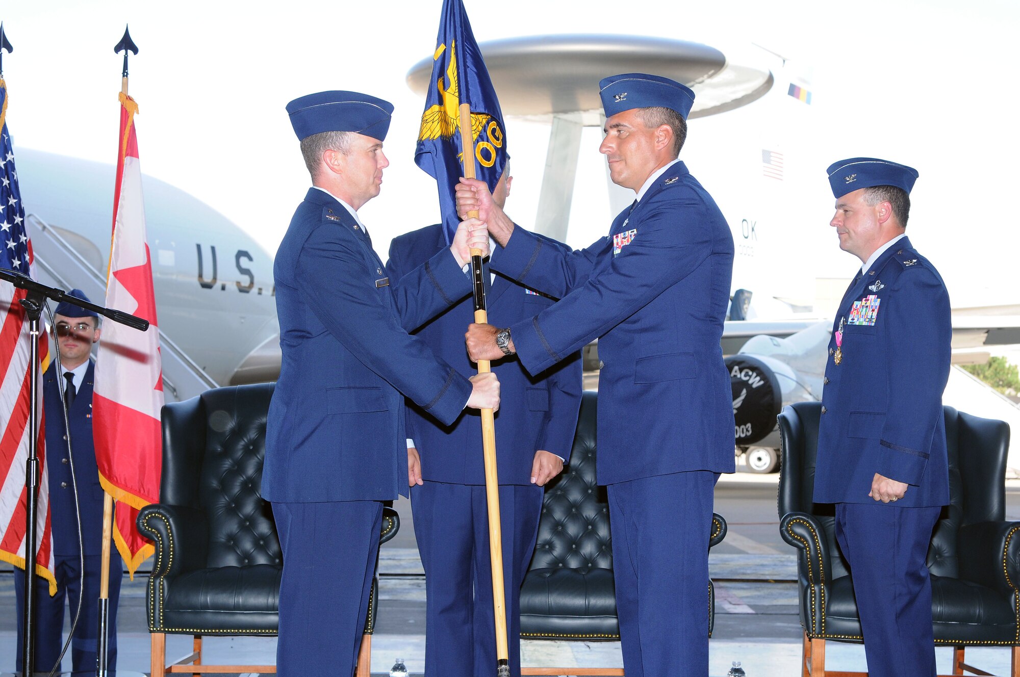 Col. John J. Cooper, center, passes the guidon to Col. Gregory M. Guillot, commander of the 552nd Air Control Wing and officiating officer, to officially signal completion of the change of command for the 552nd Operations Group during a ceremony July 17 inside Bldg. 230, Dock 2, at Tinker Air Force Base. Colonel Cooper, who spent this past year attending the Naval War College at Newport Naval Station, R.I., assumed command of the 552nd OG from Col. Gregory D. Roberts, right. Colonel Cooper will now be responsible for creating policy and commanding operations of E-3 aircraft throughout the world, totaling $5 billion in Air Force resources. He will lead four operational flying squadrons, two training squadrons and an operations support squadron. Colonel Cooper will lead more than 1,900 personnel and mange a $68 million budget. (Air Force photo by David Faytinger)