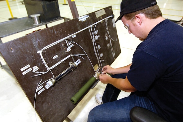 Chance Stevens came to the boom shop three months ago and with seasoned personnel working with him, is enjoying learning his work. Stevens follows a wiring cable outline to reconnect electrical for lights and hydraulics that are installed in the tail cone. The system will then be tested as used on the boom before installed in a waiting tail cone. In flight, the lights help guide the refueler and the receiver in making a safe connection before refueling begins.(U.S. Air Force photo/Margo Wright) 