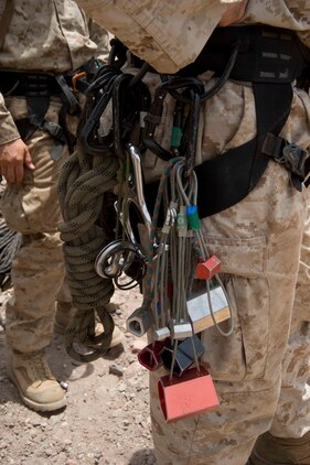 Rock climbing gear hangs from a U.S. Marine’s harness July 22. French and U.S. Marines participated in an assault climbing course in the rugged terrain of the Arta Range July 19 - 30. The gear used by the Marines for rock climbing can include safety helmets, ropes, belay devices, carabiners, climbing harnesses, climbing shoes, quickdraws, crampons, and ice axes.