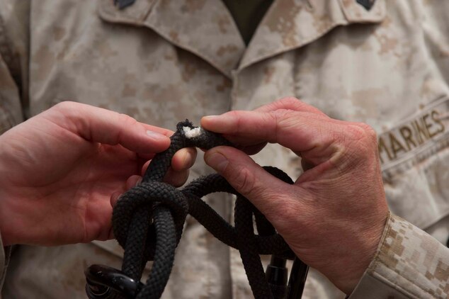 U.S. Marine Sgt. Jason Schmus finds damage in a climbing rope that a falling rock had caused here July 22. French and U.S. Marines participated in an assault climbing course in the rugged terrain of the Arta Range July 19 - 30. The rope was replaced to ensure the safety of all climbers during the assault climbers training.