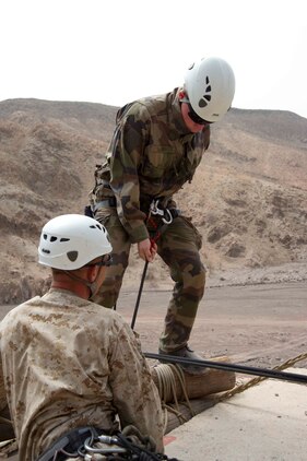 French marine Sgt. Steven Rey, 5th Marine Regiment, prepares to jump off and repel down a cliff July 22 under the supervision of U.S. Marine Master Sgt. Chris Brueggeman, 24th Marine Expeditionary Unit assault climbers instructor. French and U.S. Marines participated in an assault climbing course in the rugged terrain of the Arta Range July 19 - 30.
