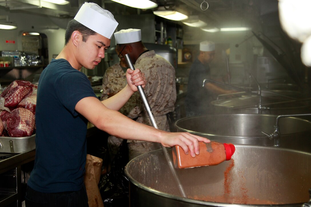 Petty Officer 3rd Class Marl L. Gonzales, culinary specialist, USS Peleliu, adds seasoning for a meal he is preparing in the ship’s galley for the Marines and sailors of the 15th Marine Expeditionary Unit and Peleliu Amphibious Ready Group, July 22. Gonzales, 22, is from Manila, Philippines.