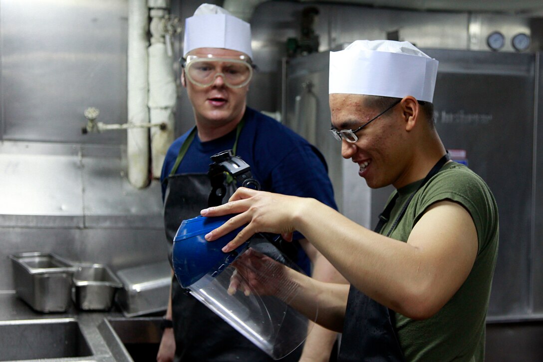 Lance Cpl. Paul D. Hoang (right,) electro-optical ordnance repairer, Headquarters and Service Company, Battalion Landing Team 3/5, 15th Marine Expeditionary Unit, and Airman Jiri Gajdacek, USS Peleliu, clean dishes in the ship’s galley, July 22. Hoang and Gajdacek are both temporarily serving as mess men, a duty assigned to Marines and sailors to assist the food service specialists who prepare the meals for the Marines and sailors of the 15th Marine Expeditionary Unit and Peleliu Amphibious Ready Group. Hoang, 20, is from Houston, and Gajdacek, 30, is from Havirov, Czech Republic.