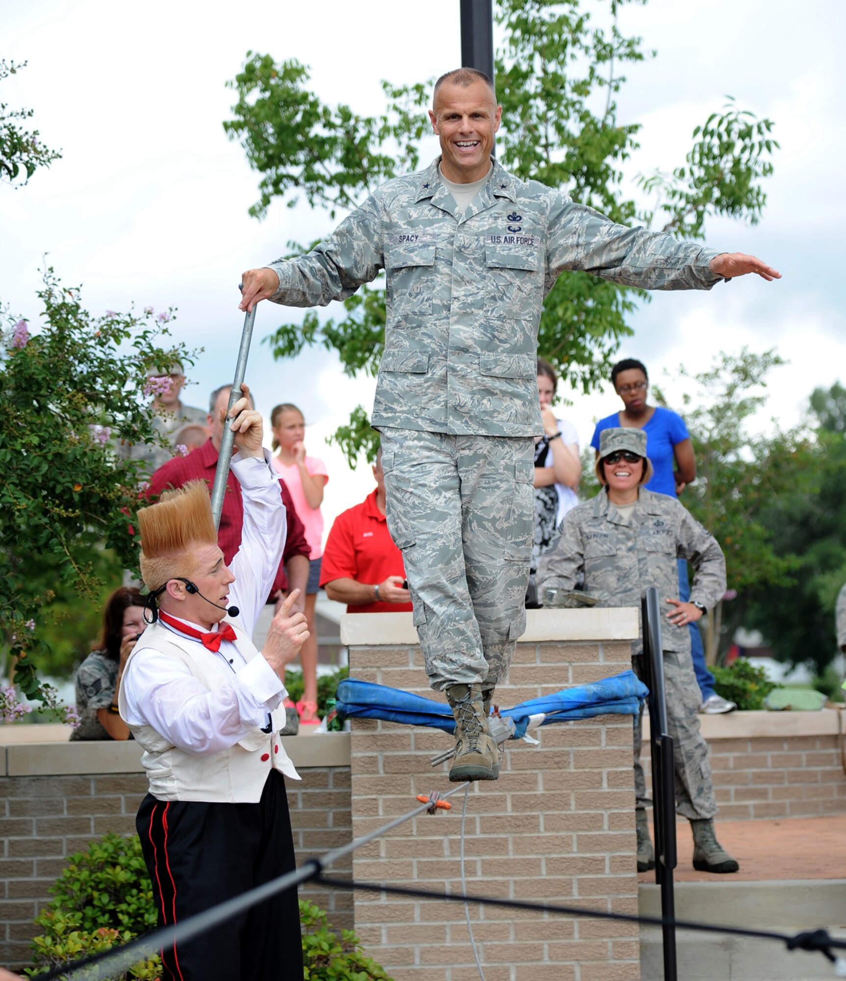 Bello Nock, comedic daredevil and international circus star for Fata Morgana, assists Brig. General Brad Spacy, 81st Training Wing commander, as he successfully walks across a tight rope during a military appreciation show for Keesler families July 21, 2012, at the Bay Breeze Event Center, Keesler Air Force Base, Miss.  Fata Morgana, an Italian phrase meaning optical illusion, featured a small number of various acts throughout the show.  (U.S. Air Force photo by Kemberly Groue)