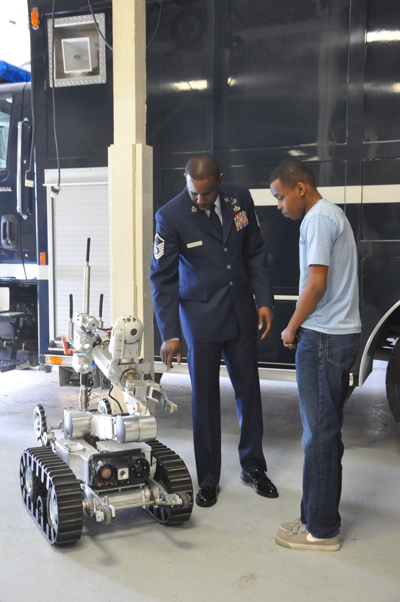 Air Force Master Sgt. Gerald Davis shows his son, Nehemiah Davis, a robot used by explosive ordnance disposal troops to disable improvised explosive devices just before he receives a Bronze Star Medal for his work in Afghanistan as an EOD supervisor.  Air Force Staff Sgt. Wesley Kory also received a Bronze Star Medal for his work as an EOD team leader clearing 2,000 miles of urban terrain and supply routes. (U.S. Air Force photo/Staff Sgt. Cynthia Spalding)