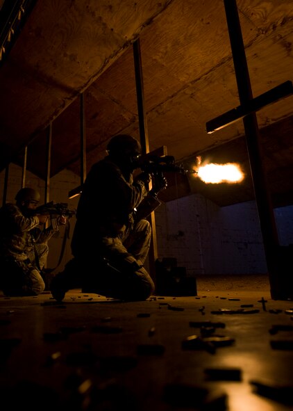 Senior Airman Nicholas Navarro, left, and Senior Airman Alexi Patterson, right, 7th Security Forces Squadron, fire M-4 Carbines during night-fire training July 19, 2012 at Dyess Air Force Base, Texas. Airmen fired 70 rounds from an M-4 Carbine mounted with a PVS-14 in front of a red dot sight. The scope collects small amounts of light and amplifies it, allowing the shooter to see down range in low-light situations. The targets were 25 feet away, but distances are simulated between 70 and 300 meters. (U.S. Air Force photo by Airman 1st Class Damon Kasberg/Released)