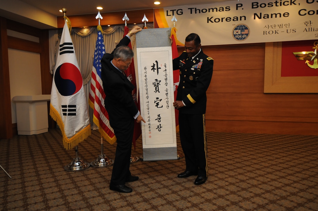 SEOUL, Republic of Korea — Suh Jin-sup, chairman of the Republic of Korea-U.S. Alliance Friendship Association, points to Chinese characters on a scroll as he reads them to Lt. Gen. Thomas Bostick, Commanding General of the U.S. Army Corps of Engineers, during a "Korean naming ceremony" July 16, 2012. Bostick was given the honorific Korean name Park Bo-taek by the association during his visit to the Republic of Korea, where he met with U.S. and Korean military officials and toured the multi-billion dollar construction project at U.S. Army Garrison Humphreys, about 40 miles south of Seoul. The Corps of Engineers has about 37,600 military and civilian personnel providing project management and construction support in more than 100 countries.