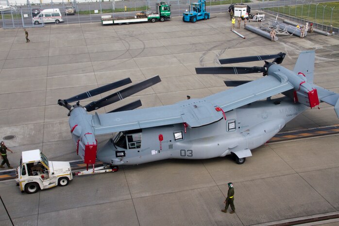 A Marine Medium Helicopter Squadron 265 Marine uses a utility tractor to guide a MV-22 Osprey off the cargo ship Green Ridge at the Marine Corps Air Station Iwakuni harbor here July 23, 2012. This marks the first MV-22 Osprey aircraft deployment to Japan and a milestone  in the Marine Corps' process of replacing CH-46E helicopters with the MV-22 Osprey, a highly-capable, tilt-rotor aircraft which combines the  vertical capability of a helicopter with the speed and range of a fixed-wing aircraft.