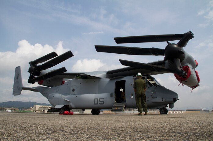 A Marine Medium Helicopter Squadron 265 Marine watches as an MV-22 Osprey rotates its wings into position during a series of routine checks at the Marine Corps Air Station Iwakuni flight line here July 23, 2012. This marks the first MV-22 Osprey aircraft deployment to Japan and a milestone in the Marine Corps' process of replacing CH-46E helicopters with the MV-22 Osprey, a highly-capable, tilt-rotor aircraft which combines the vertical capability of a helicopter with the speed and range of a fixed-wing aircraft.
