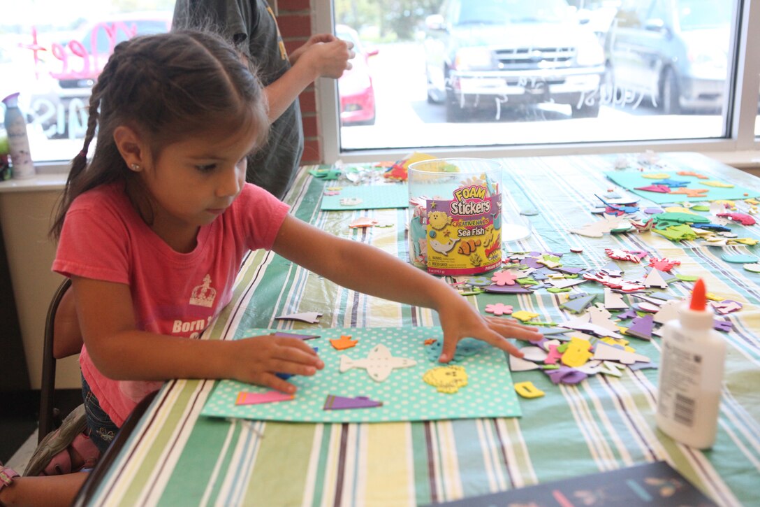 Camille, a military dependent, works on her art project during the Summer Kids Club hosted by the Armed Services YMCA aboard Marine Corps Base Camp Lejeune’s Tarawa Terrace residential area July 19. The youngsters were spellbound as they focused on creating masterpieces made of colorful foam cut-outs and an excessive amount of glue.  