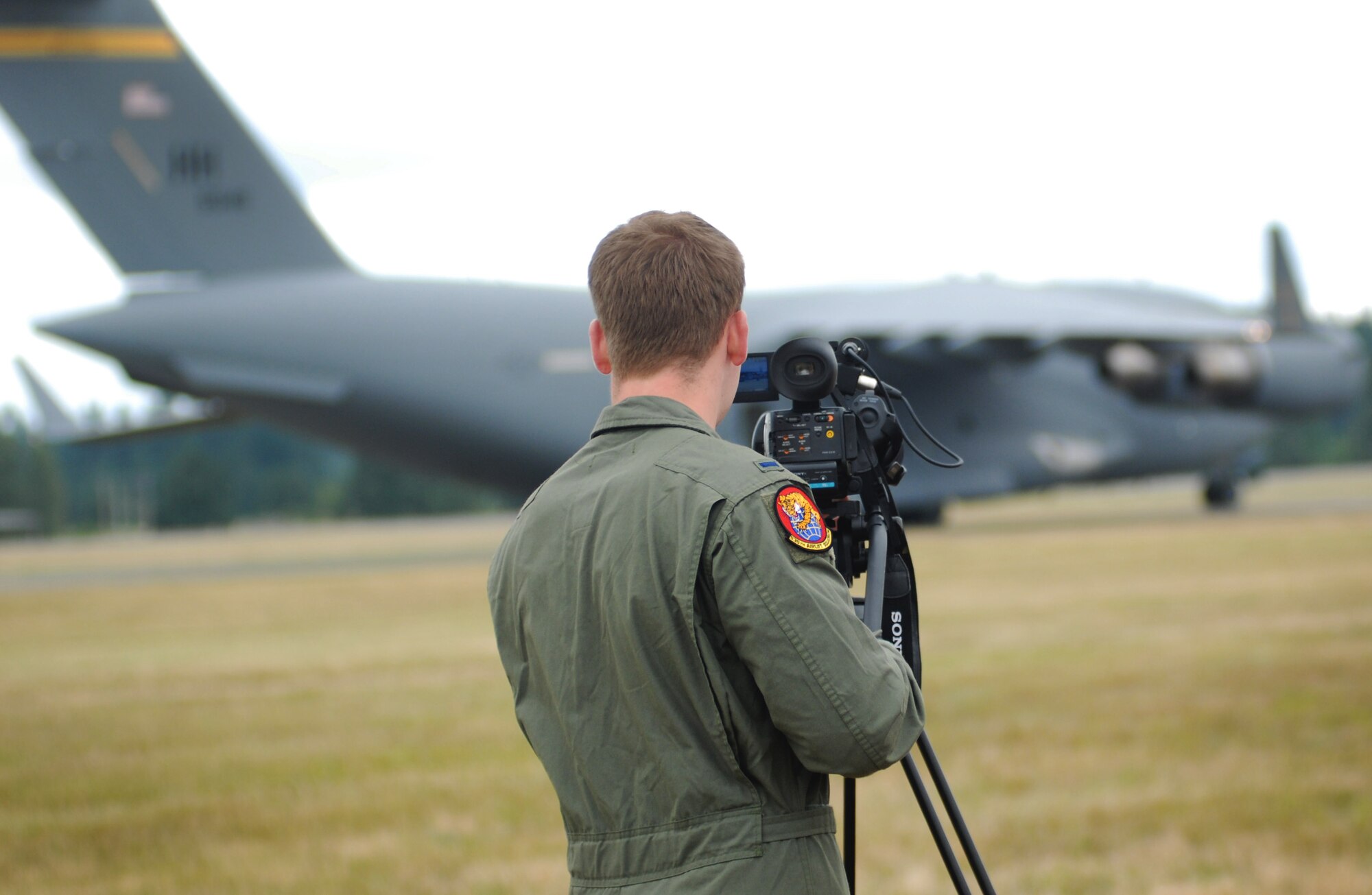1st Lt. James Hammelman, videographer for the Pacific Air Forces C-17 Aerial Demonstration Team, records the team's performance at the Joint Base Lewis-McChord Air Expo 2012 at McChord Field, Washington July 22. The JBLM Air Expo 2012 featured 20 aerial performers and over 40 static aircraft displays. (U.S. Air Force photo by 2nd Lt. Jessica Colby) 