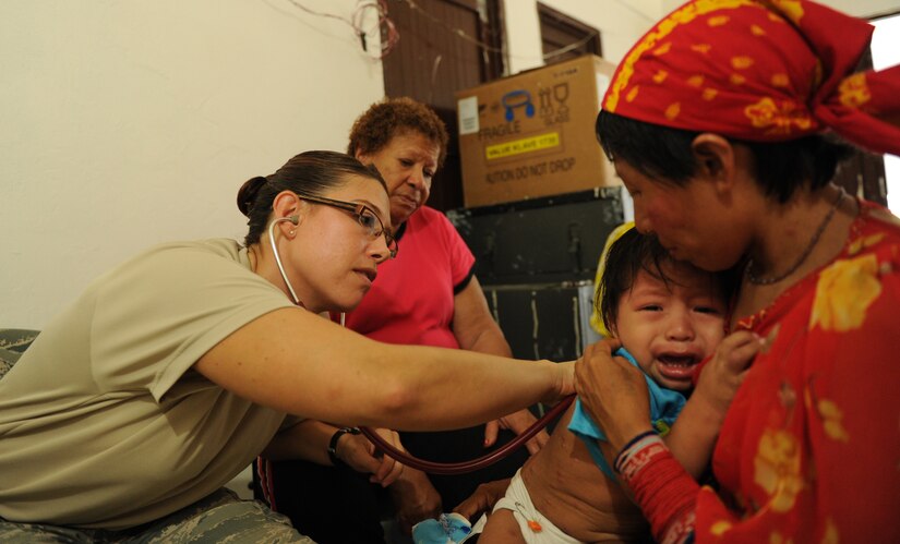 Air Force 1st Lt. Daniela Feldhausen, physician assistant, JTF-Bravo examines the child of a Guna woman, while Lilia Lambert, a translator from the Veterans of Foreign Wars in Panama assists with translating during a Medical Readiness Training Exercise, on the Island of Carti off the northeastern coast of Panama. (Official Photo by Tech. Sgt. Brannen Parrish)