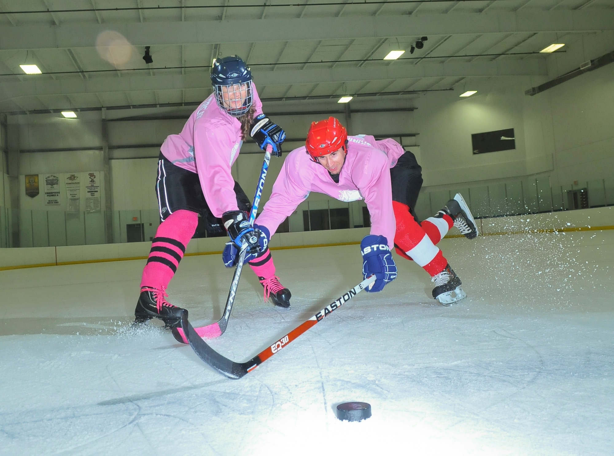 SAN ANTONIO -- 1st Lt. Andrew Caulk, right, of the Air Force Intelligence, Surveillance and Reconnaissance Agency and 1st Lt. Jennifer Caulk from the 453 Electronic Warfare Squadron at Lackland Air Force Base, Texas, battle for the puck July 20 at the Ice and Golf Center at Northwoods here, following their game in the Adult Recreational Hockey League. Hockey is one of many sports the duo plays for fitness, fun and quality time together. (U. S. Air Force photo  by William Belcher)     