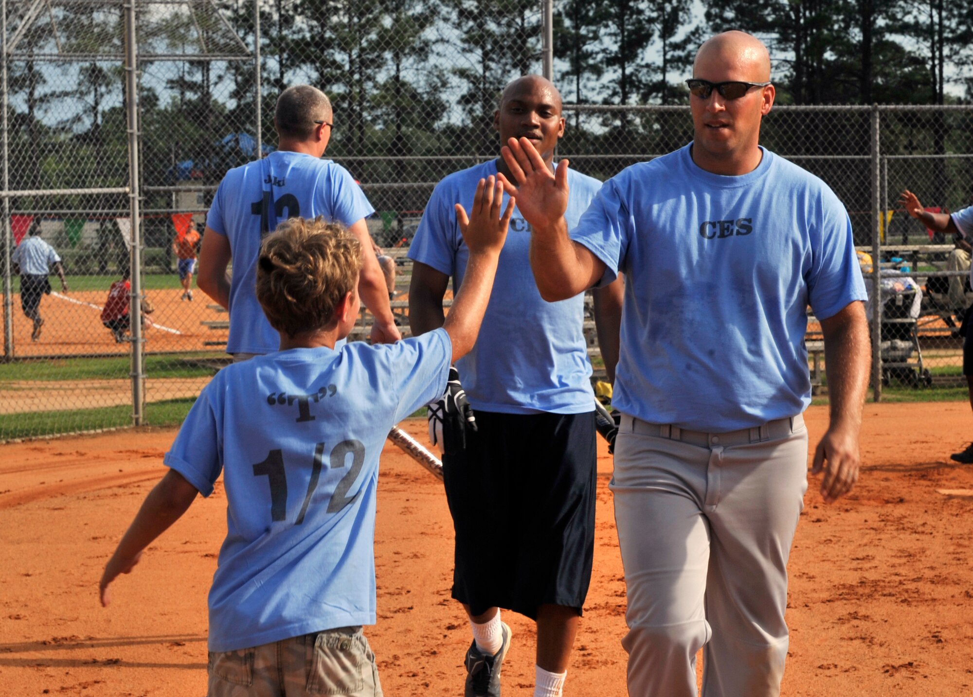 U.S. Air Force Staff Sgt. Travis Bowersock, 20th Civil Engineer Squadron structures craftsman, high-fives his son during a softball game at Shaw Air Force Base, S.C., July 17, 2012. Every year Shaw holds softball intramural games which many teams play against each other to get to the playoffs. (U.S. Air Force photo by Senior Airman Tabatha McCarthy/ Released)
