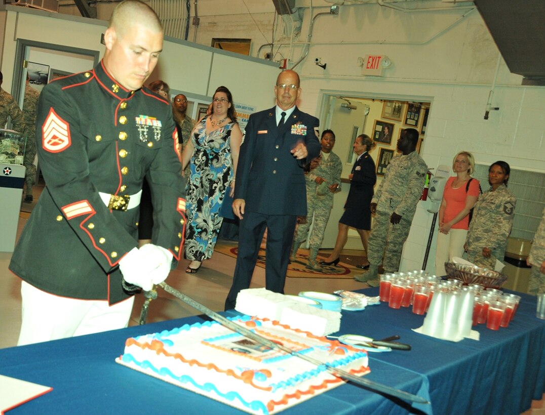 Marine Corps Staff Sgt. Michael E. Johnson of Air Force Mortuary Affairs Operations, Dover Air Force Base, Del., cuts a cake July 14, 2012, following a retirement ceremony for Senior Master Sgt. Randall B. Anderson (shown at rear), chief of education and training for the 512th Airlift Wing, an Air Force Reserve unit at Dover AFB. Anderson served on active-duty with the Marines before transferring to the Air Force Reserve and working as an air reserve technician at Dover for 20 years. The cake featured the Air Force coat of arms, the Marine Corps seal and a rendering of Marines raising the U.S. flag on Iwo Jima in World War II. (Courtesy photo)