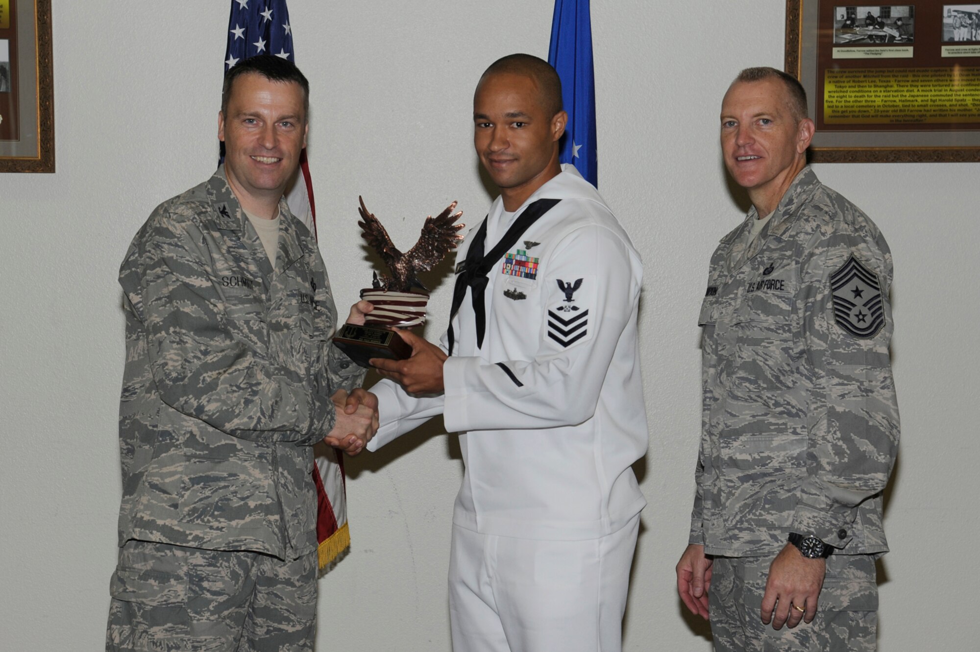 Col. Thomas Schmidt, 17th Training Wing Vice Commander, and Chief Master Sgt. Scott Lumpkin, 17th TRW Command Chief, present the Team Goodfellow NCO of the Quarter to U.S. Navy Petty Officer 1st Class Isaac Berwick, Navy Center for Information Dominance Detachment, during the wing quarterly awards ceremony, July 24. (U.S. Air Force photo by Staff Sgt. Austin Knox)
