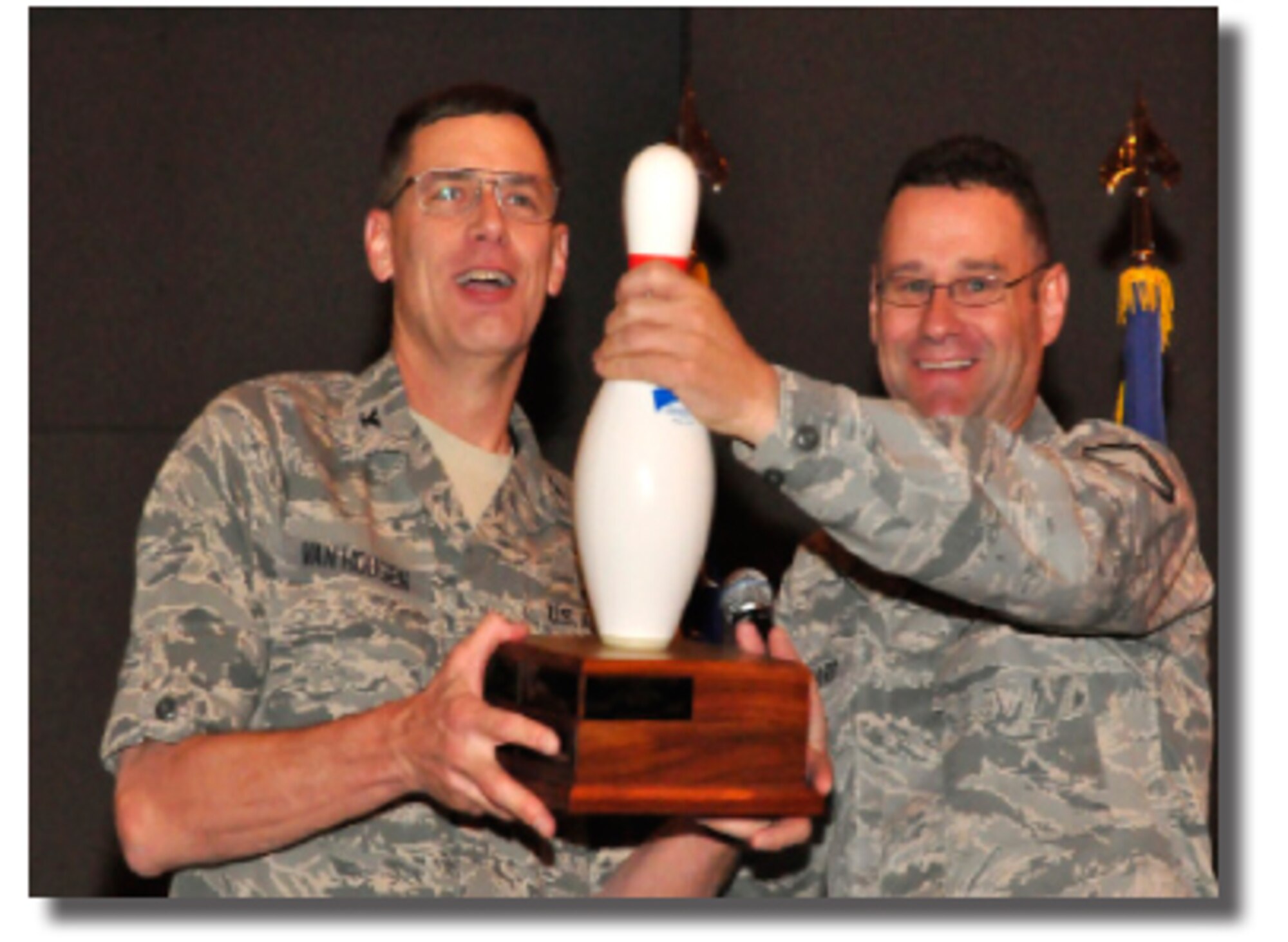 302nd Airlift Wing Family Day Bowling Tournament organizer Senior Master Sgt. Terry Brassard, on right, presents Col. James Van Housen, 302nd Maintenance Group Commander the Traveling Bowling Pin Trophy during the wing's April Commander's Call. “THE Maintenance Team” repeated as tournament champions by beating their closest competitor by more than 450 pins. (U.S. Air Force photo/Staff Sgt. Stephen Collier) 