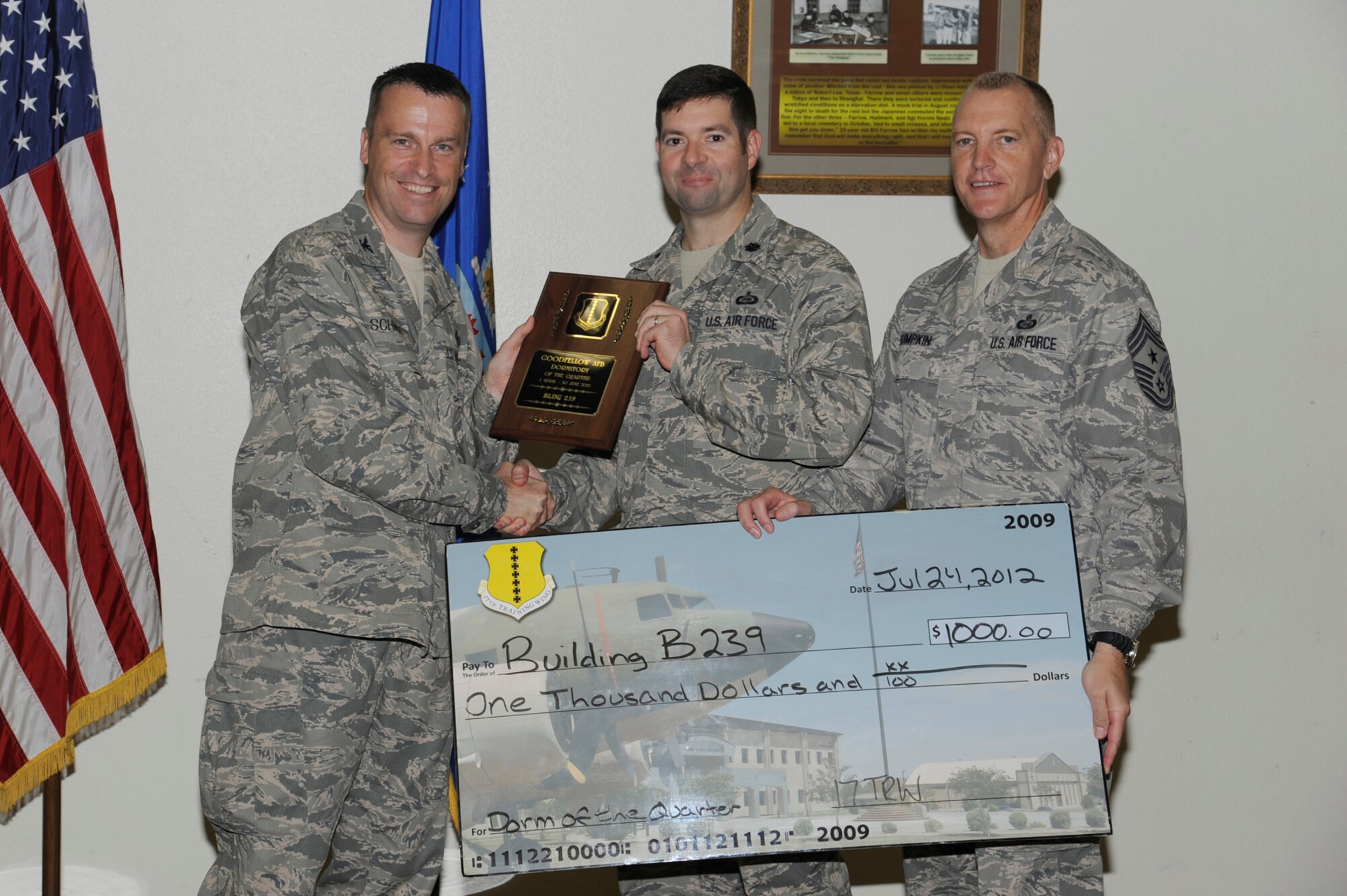 Col. Thomas Schmidt, 17th Training Wing Vice Commander, and Chief Master Sgt. Scott Lumpkin, 17th TRW Command Chief, present Lt. Col. Scott Nahrgang, 316th Training Squadron commander, with the Team Goodfellow, Dormitory of the Quarter for Building 239 during the wing quarterly awards ceremony July 24. (U.S. Air Force photo by Staff Sgt. Austin Knox)