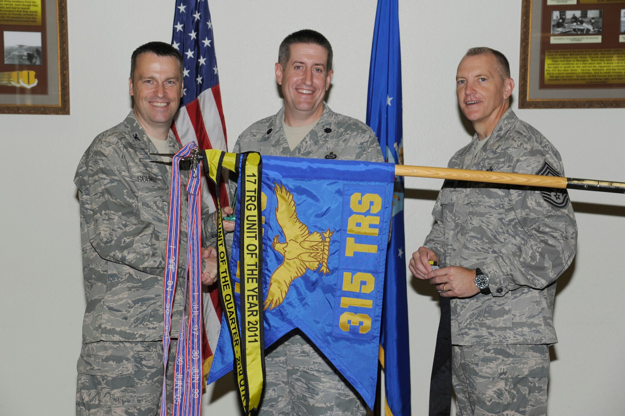 Col. Thomas Schmidt, 17th Training Wing Vice Commander, and Chief Master Sgt. Scott Lumpkin, 17th TRW Command Chief, present the 17th Training Wing Unit of the Quarter to Lt. Col. Christopher Huisman, 315th Training Squadron Commander, during the wing quarterly awards ceremony July 24. The 315th TRS also received the Team Goodfellow Unit of the Quarter. (U.S. Air Force photo by Staff Sgt. Austin Knox) 