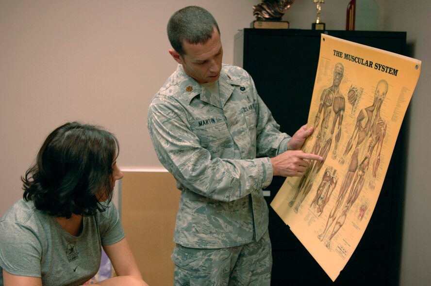 U.S. Air Force Maj. Justin Martin, 20th Medical Group physical therapy flight commander and a native of Fairfield, Idaho, shows U.S. Army Lt. Col. Tess Wardell, Third Army/ARCENT information operation branch chief and a native of Elizabethtown, Ky., the muscle group that she injured, Shaw Air Force Base, S.C., July 23, 2012. Wardell arrived at the clinic for an initial examination when she began having pain in her thigh, which disrupts her physical training. After the examination, Martin taught her stretches that would work her muscles and reduce her pain. (U.S. Air Force photo by Airman 1st Class Krystal Jeffers/Released)