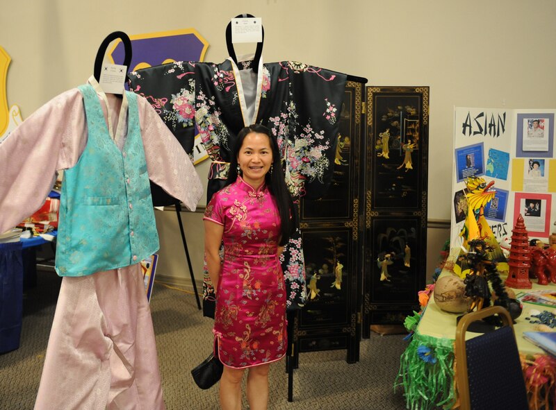 Capt. Shaoping Mo, 2nd Medical Support Squadron, poses in front of clothing from various Asian cultures during Multicultural Day on Barksdale Air Force Base, La., July 20. The Asian American booth displayed various weaponry, sculptures, clothing and facts about their culture. (U.S. Air Force photo/Airman 1st Class Benjamin Gonsier)(RELEASED)