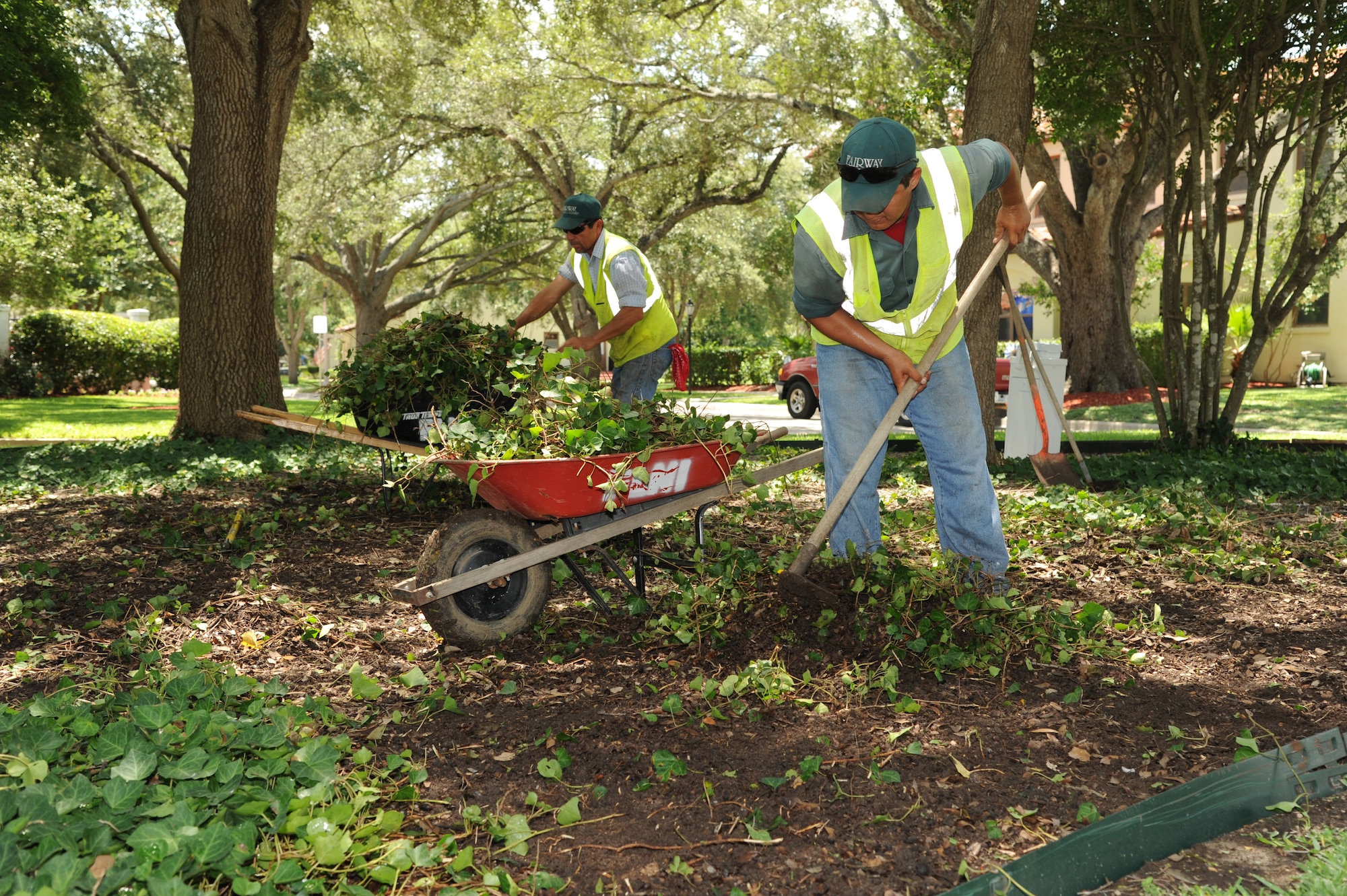 Hector Montoya (left), and Hector Perez, Fairways Landscaping service professionals, clear ground clutter around the Clark House on Joint Base San Antonio-Randolph, Texas, July 24. (U.S. Air Force photo by Rich McFadden) 