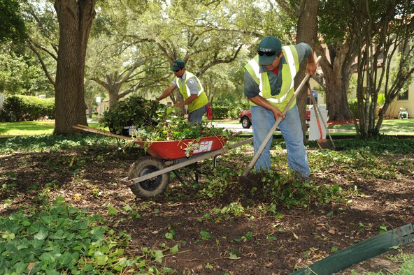 Hector Montoya, left, and Hector Perez clear ground clutter around Clark House at Joint Base San Antonio-Randolph, Texas, July 24, 2012. Montoya and Perez are with Fairways Landscaping. (U.S. Air Force photo/Rich McFadden)