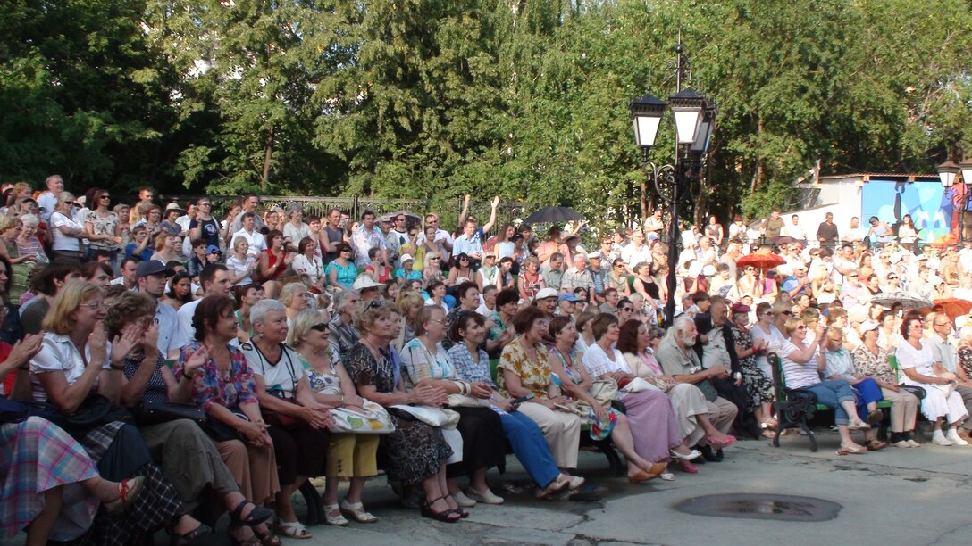A crowd cheers on the quintet at an outdoor concert 