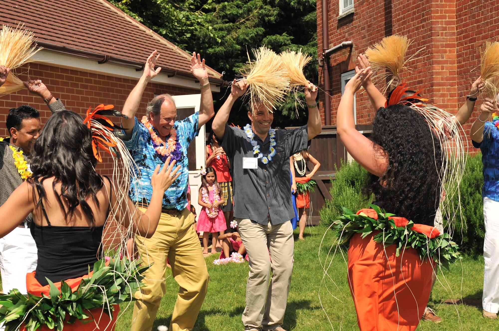 RAF MILDENHALL, England – Base personnel and distinguished members of the local community, dance alongside members of the Halau O U’ilani dance group during the New Mayor’s Barbecue held on base July 21, 2012. The annual event hosted by the 100th Air Refueling Wing commander, consisted of wing mission and economic impact briefs and ended with a Hawaiian luau-themed social. (U.S. Air Force photo/Senior Airman Jerilyn Quintanilla)