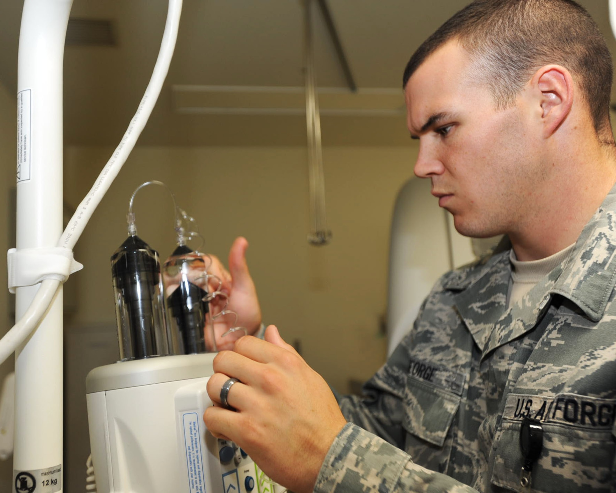 U.S. Air Force Staff Sgt. Mike George, 35th Medical Group diagnostic imaging technologist, taps the IV vials prior to performing a CT scan at Misawa Air Base, Japan, July 24, 2012. Technologists tap the cylinders filled with IV contrast and saline to get rid of any bubbles in the vials that could prove fatal to the patient. (U.S. Air Force photo by Airman 1st Class Kenna Jackson/Released)