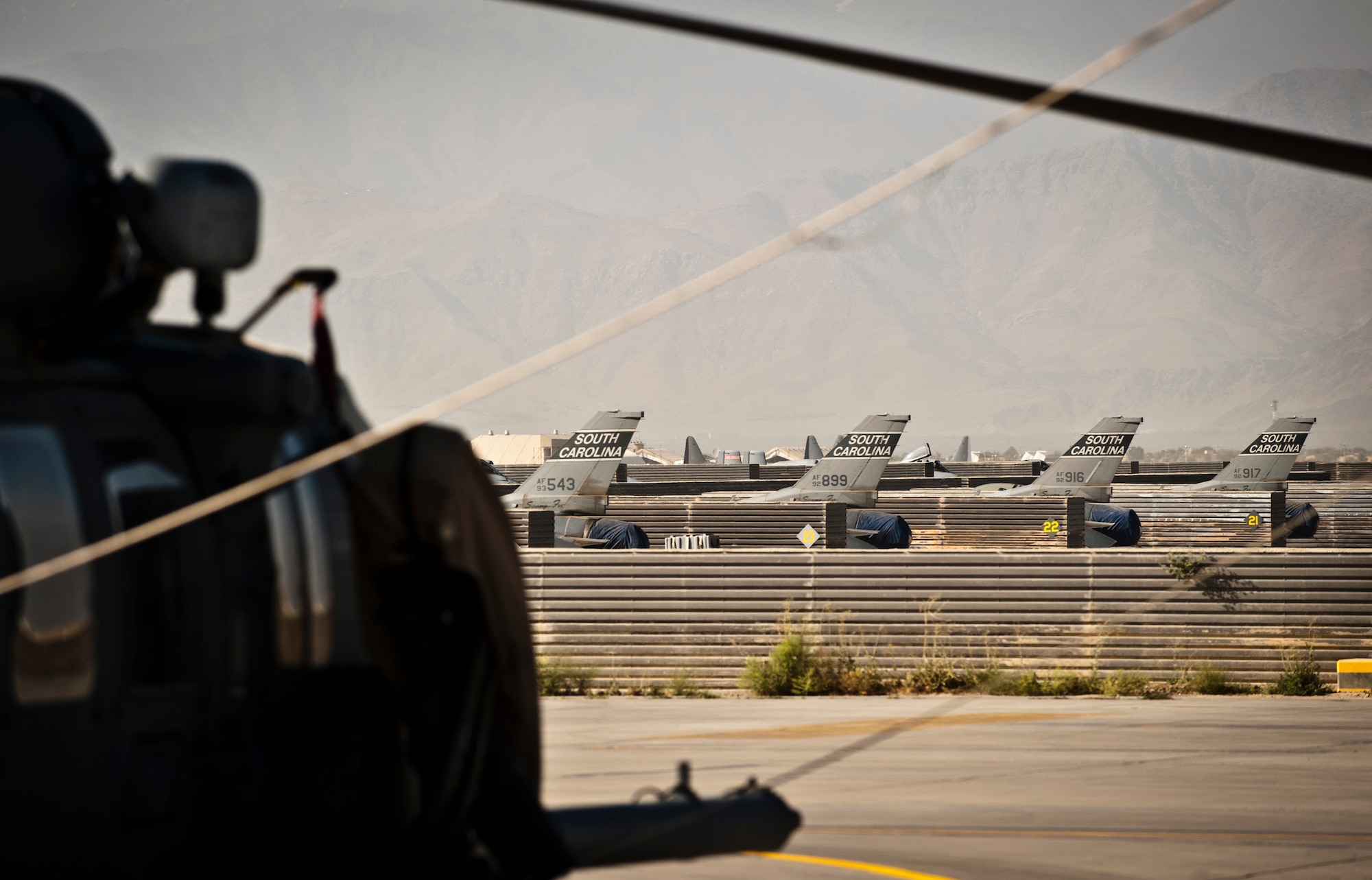 An HH-60 Pave Hawk overlooks four F-16 Fighting Falcons assigned to Kandahar Airfield parked at Bagram Airfield, Afghanistan, July 21, 2012. The F-16s were temporarily moved to Bagram while Airmen made improvements to Kandahar’s ramp. (U.S. Air Force Photo/Capt. Raymond Geoffroy)