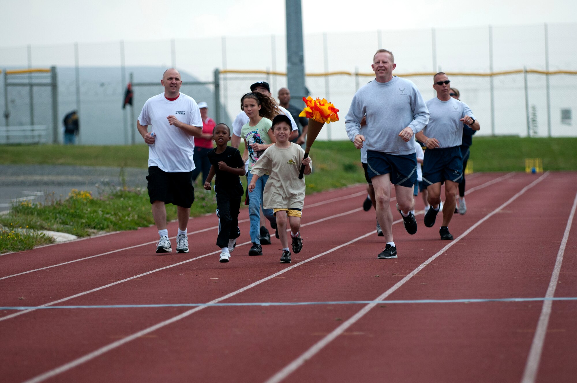SPANGDAHLEM AIR BASE, Germany -- Ethan Guinn runs with an Olympic torch during the Olympic Day celebration near the Skelton Memorial Fitness Center here July 21.  Col. Joseph McFall, 52nd Fighter Wing vice commander,  Col. Scott Calisti, 52nd Mission Support Group commander, Maj. Catherine Logan, 52nd Force Support Squadron commander, and Chief Master Sgt. Matthew Grengs, 52nd Fighter Wing command chief, joined Ethan during the run. (U.S. Air Force photo by Airman 1st Class Gustavo Castillo/Released)