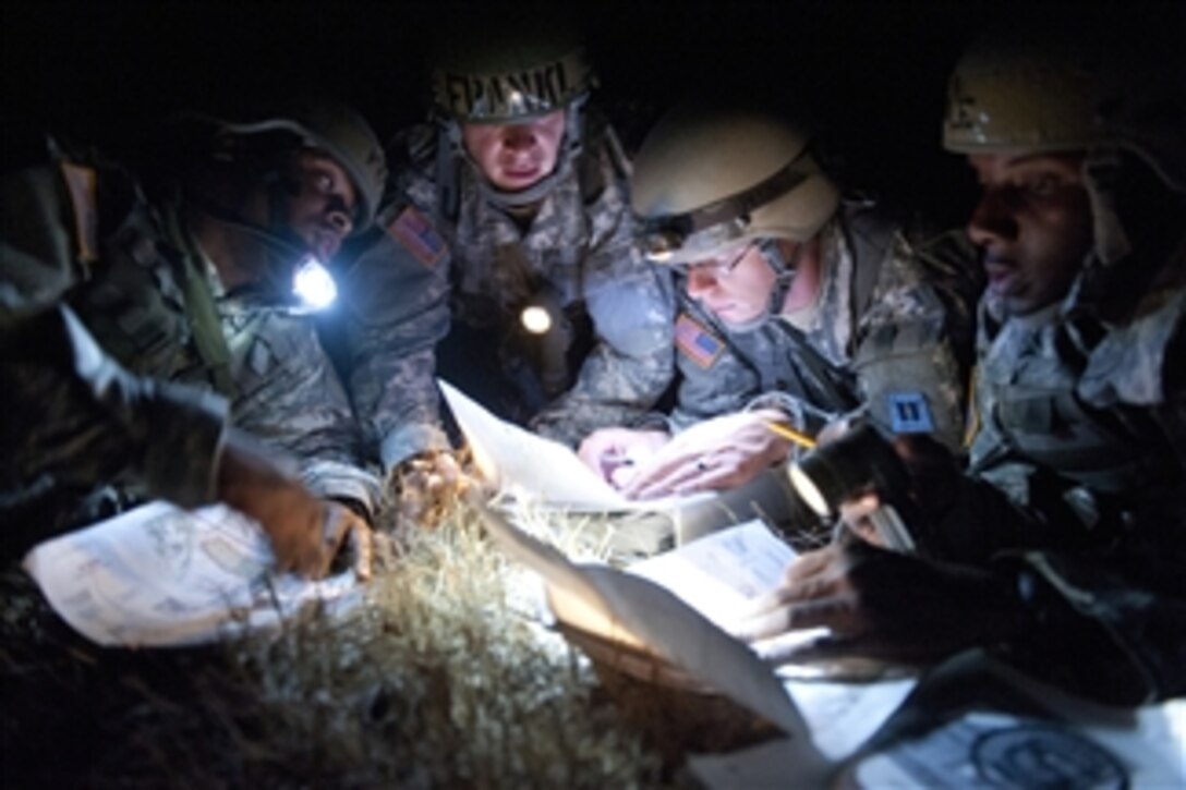 From left to right, U.S. Army Officer Candidates Landon Foy, Paul Frankl, Phillip Bettis and Damien Cole check each other's points for accuracy during a night land navigation exercise at Fort Meade, S.D., on July 19, 2012.  Officer candidates work as a team on the first night of land navigation and will work individually for a passing grade the second night.  