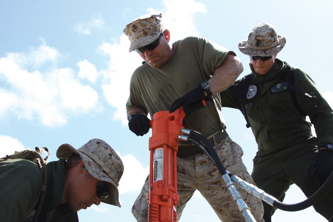 Lt. Col. Thomas E. Frederick, center, mans a jackhammer with Sgt. Joseph R. Pachco, left, and Lance Cpl. Devin J. Ward at Tinian's West Field, May 18th, during Exercise Geiger Fury 2012. The Marines use the jackhammer to drive M-31 arresting gear stakes into the runway at the field. Frederick is the executive officer of Marine Aircraft Group 12, 1st Marine Aircraft Wing, III Marine Expeditionary Force. Pachco and Ward are expeditionary airfield technicians with Marine Wing Support Squadron 171, MAG-12, 1st MAW, III MEF.