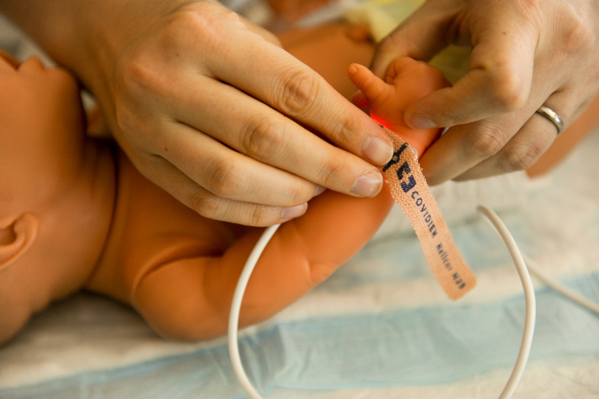 U.S. Air Force Capt. Rabekah Carlisle, 18th Medical Group neonatal intensive care unit nurse, secures a heart monitor to a fake baby while training on Camp Lester Naval Hospital, Japan, July 20, 2012. The NICU is the second largest in the Air Force and is also able to get a crew in the air in three hours to help tiny patients in need. (U.S. Air Force photo/Airman 1st Class Brooke P. Beers)
