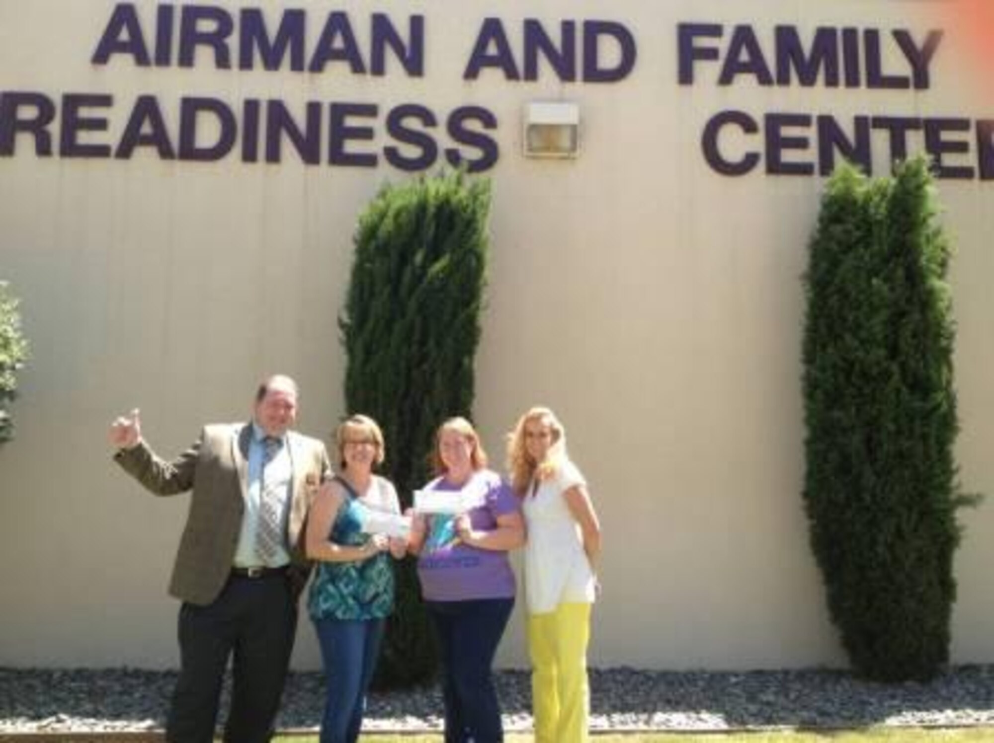 Sasha Nunnally, spouse of Tech. Sgt. Kenneth Nunnally, 15th Air Mobility Operations Squadron deployable C2 systems section, and Anne Cook, spouse of Staff Sgt. James Cook III, 60th Diagnostics and Therapeutics Squadron clinical lab and pathology flight, pose for a photo outside the Airman and Family Readiness Center. The spouses won a bingo contest to earn a Spouse Employment Program Scholarship to learn entry-level job skills.